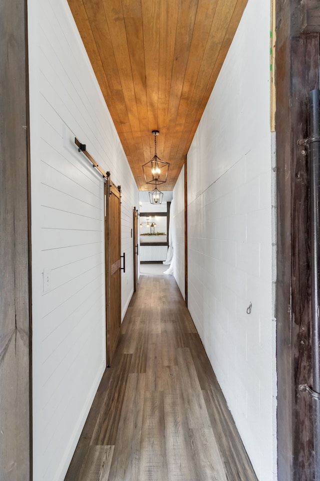 corridor featuring wood ceiling, a chandelier, dark hardwood / wood-style flooring, and a barn door