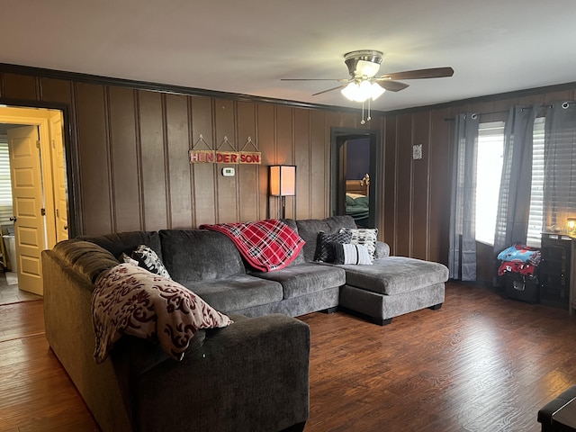 living room featuring ceiling fan, wood-type flooring, and wood walls