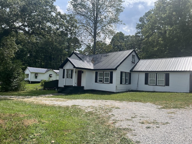 view of front of property with metal roof, a front lawn, and driveway