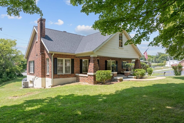 back of property featuring a chimney, roof with shingles, a yard, central AC, and brick siding