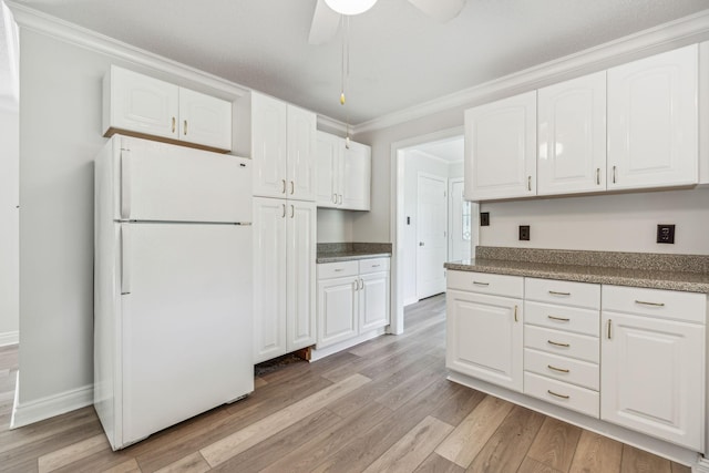 kitchen with light wood-type flooring, white cabinetry, freestanding refrigerator, crown molding, and baseboards