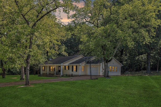 view of front of property with a lawn, driveway, fence, covered porch, and a garage