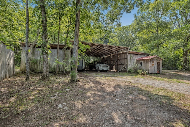 view of yard featuring an outbuilding, a wooded view, and dirt driveway