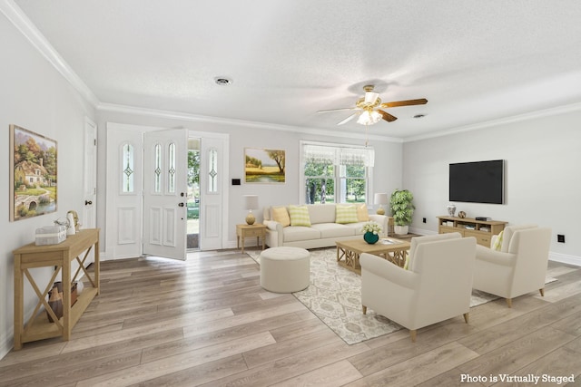 living room featuring ceiling fan, light wood-type flooring, a textured ceiling, and ornamental molding