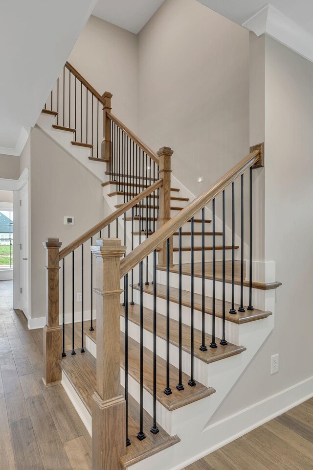 stairs with crown molding and wood-type flooring