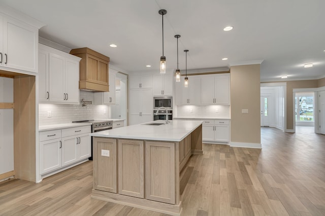 kitchen featuring white cabinets, sink, light hardwood / wood-style flooring, and a center island with sink