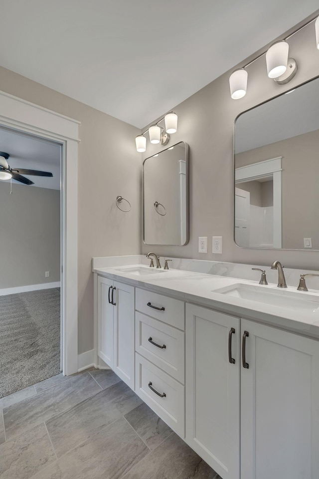 full bathroom featuring double vanity, baseboards, ceiling fan, and a sink