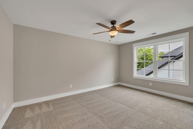 carpeted spare room featuring visible vents, ceiling fan, and baseboards