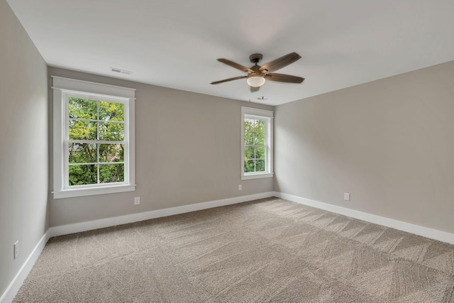 spare room featuring ceiling fan, visible vents, baseboards, and light carpet