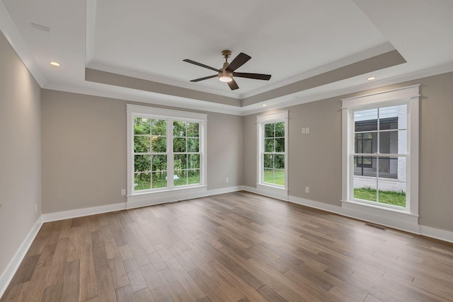 empty room featuring visible vents, baseboards, a tray ceiling, and wood finished floors