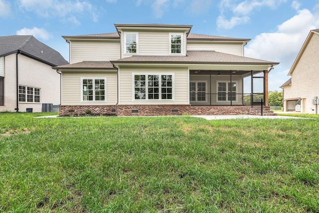 rear view of house featuring brick siding, roof with shingles, a yard, a sunroom, and crawl space