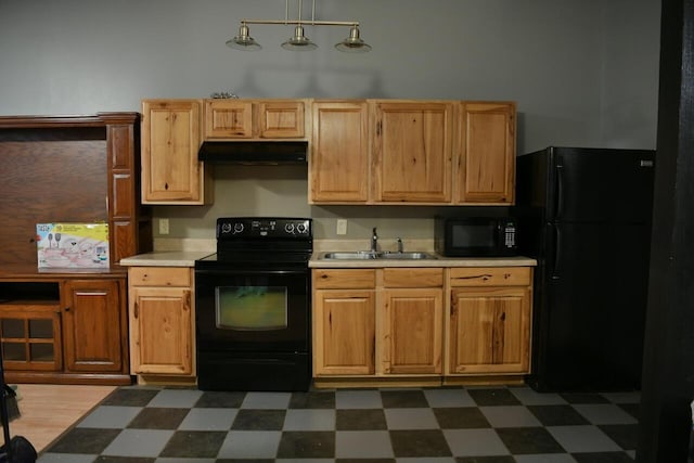 kitchen featuring dark floors, light countertops, a sink, under cabinet range hood, and black appliances
