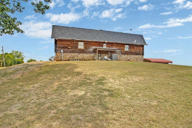 rear view of property featuring central AC and a lawn