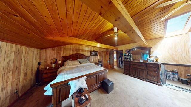 carpeted bedroom with vaulted ceiling with skylight, wood walls, and wood ceiling