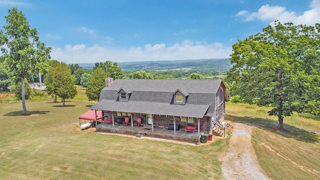 view of front of house featuring a gambrel roof, driveway, roof with shingles, a front lawn, and a chimney