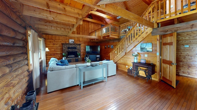 living room with a fireplace, log walls, beamed ceiling, wood-type flooring, and wood walls