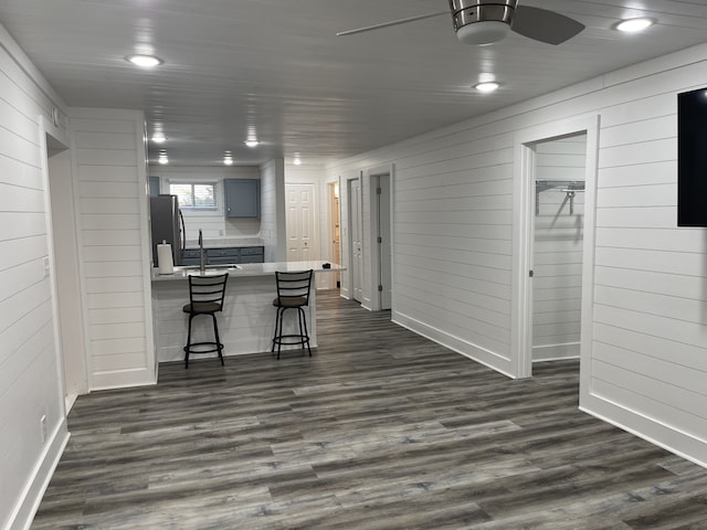 interior space with wood walls, ceiling fan, dark hardwood / wood-style floors, and indoor bar