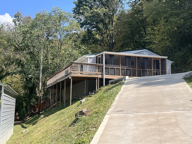 view of front of property featuring a sunroom, a deck, and a front yard