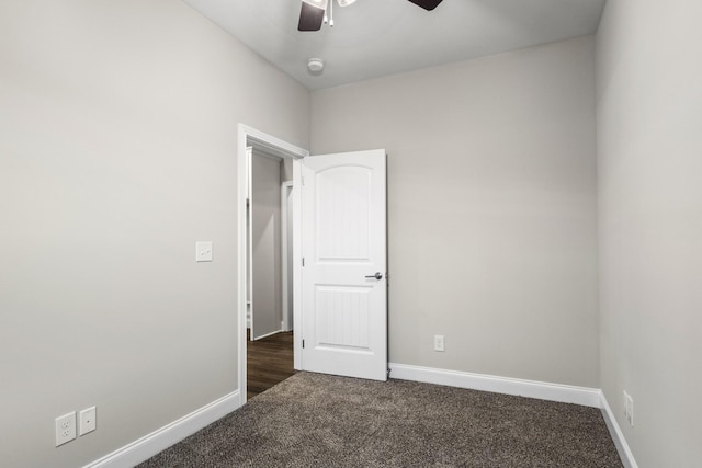 spare room featuring ceiling fan and dark carpet