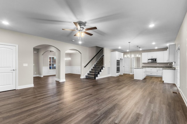 unfurnished living room with ceiling fan, sink, and dark wood-type flooring