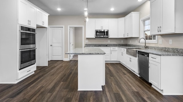 kitchen featuring a center island, stainless steel appliances, white cabinetry, and dark wood-type flooring