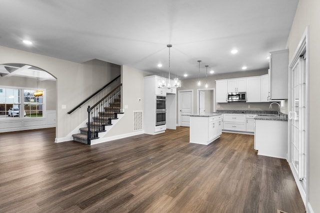 kitchen with decorative light fixtures, a kitchen island, dark hardwood / wood-style floors, and appliances with stainless steel finishes