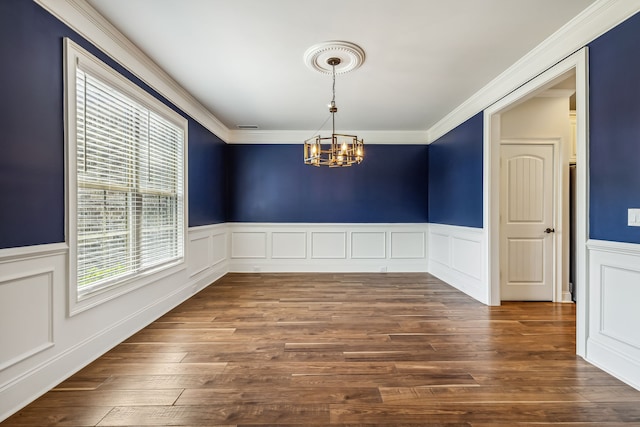 unfurnished dining area with crown molding, hardwood / wood-style flooring, and a chandelier