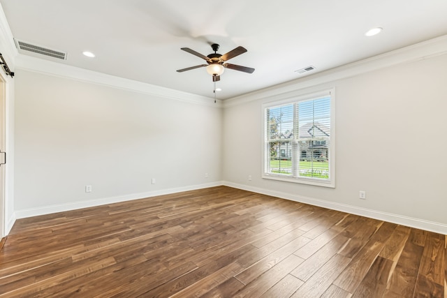 spare room featuring ceiling fan, a barn door, ornamental molding, and hardwood / wood-style floors