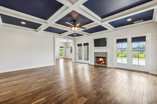 unfurnished living room featuring coffered ceiling, hardwood / wood-style floors, ceiling fan, a tiled fireplace, and beamed ceiling