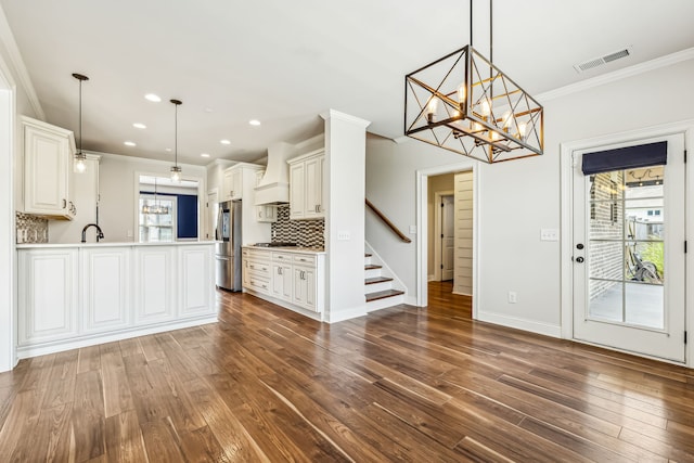 kitchen featuring tasteful backsplash, crown molding, premium range hood, wood-type flooring, and kitchen peninsula