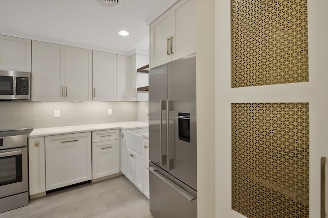 kitchen featuring appliances with stainless steel finishes, backsplash, and white cabinetry