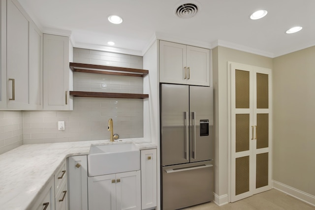 kitchen featuring backsplash, white cabinets, sink, high end fridge, and light stone counters