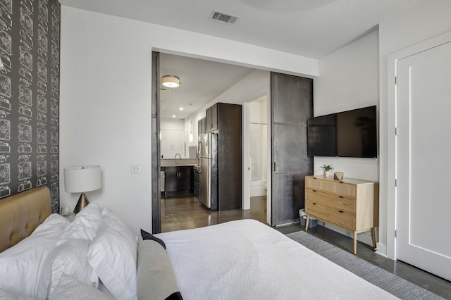 bedroom with dark wood-type flooring, ensuite bathroom, and stainless steel refrigerator