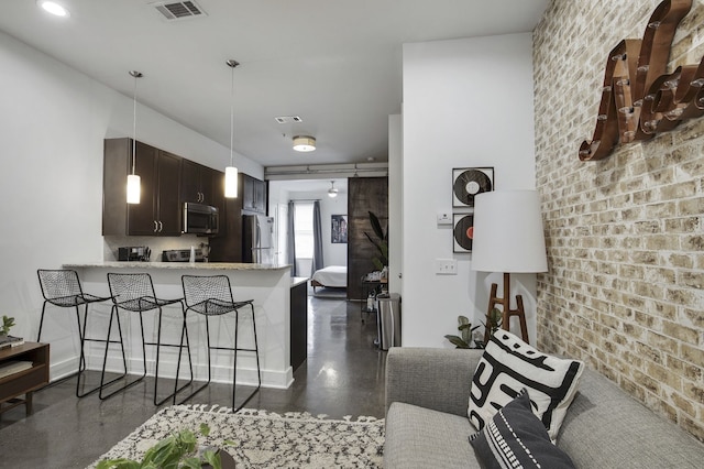 kitchen with stainless steel appliances, a breakfast bar area, kitchen peninsula, dark brown cabinetry, and decorative light fixtures