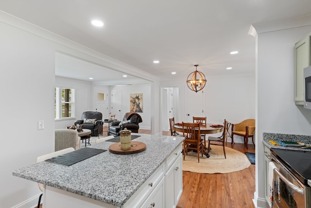 kitchen featuring hanging light fixtures, white cabinetry, crown molding, and light hardwood / wood-style floors