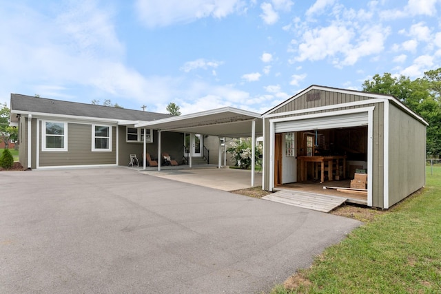 back of property with a carport, a detached garage, and an outbuilding