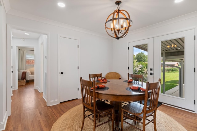 dining room with a chandelier, french doors, light wood finished floors, and ornamental molding