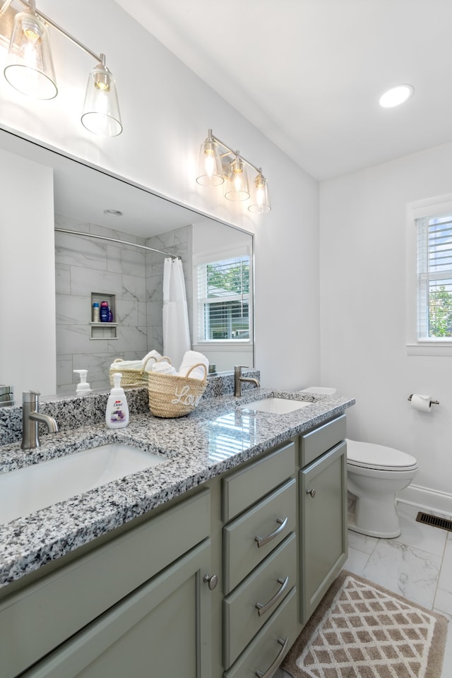 bathroom with tile patterned floors, toilet, double vanity, and plenty of natural light