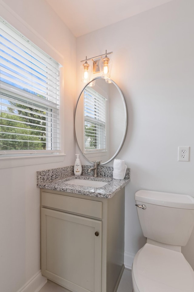 bathroom with toilet, vanity, and baseboards