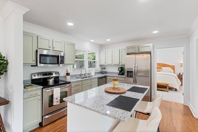 kitchen with light wood-type flooring, stainless steel appliances, light stone countertops, sink, and a kitchen island