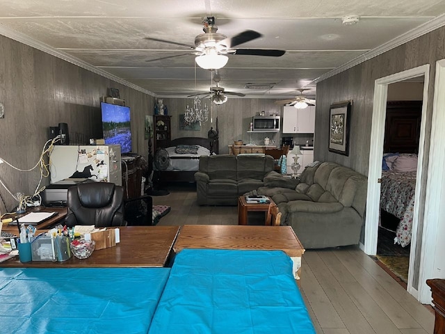 living room featuring crown molding, wood finished floors, wood walls, and a ceiling fan