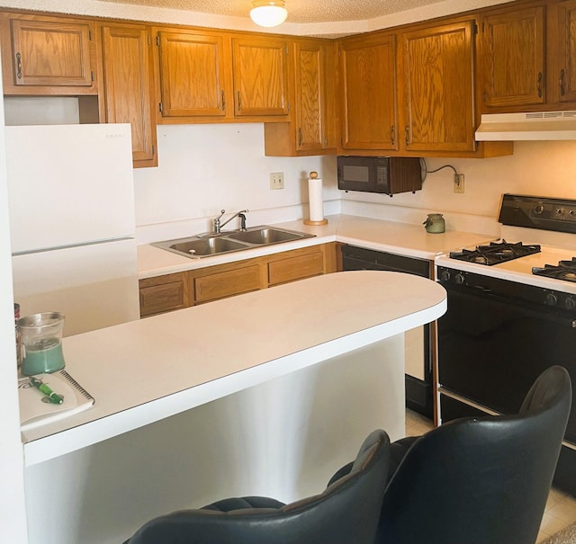 kitchen featuring freestanding refrigerator, under cabinet range hood, black microwave, a sink, and gas stove