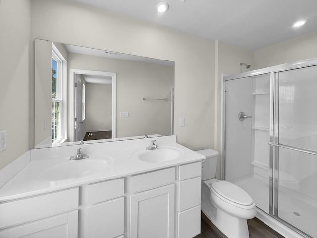 bathroom with an enclosed shower, wood-type flooring, double vanity, and toilet