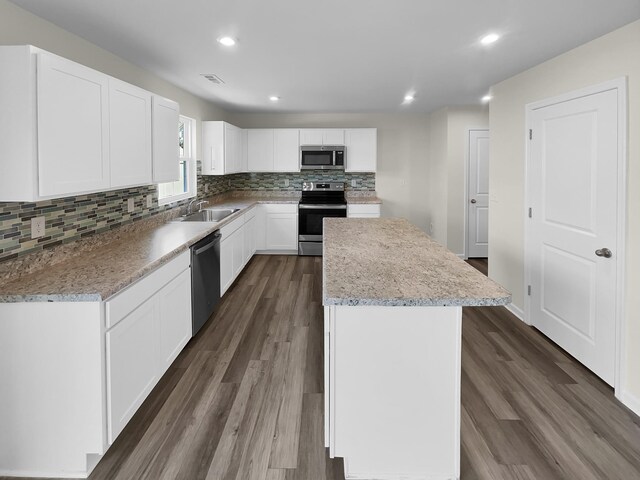 kitchen with stainless steel appliances, dark hardwood / wood-style floors, a kitchen island, sink, and white cabinetry