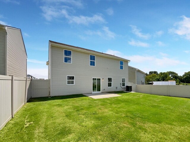 rear view of property with central AC unit, a patio area, and a lawn