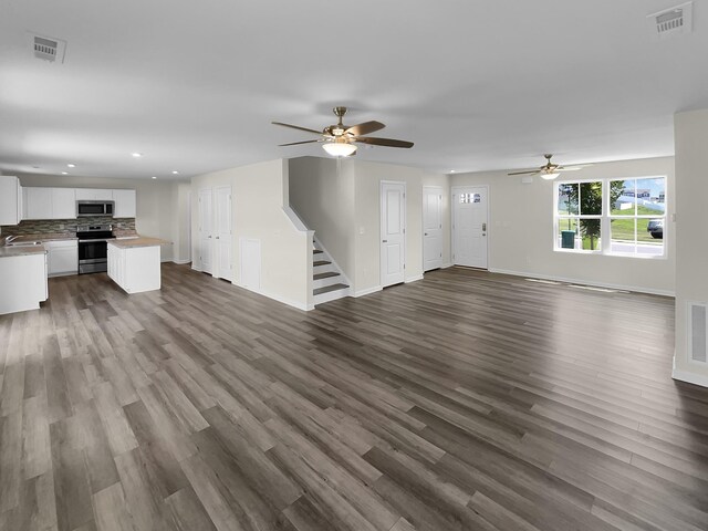 unfurnished living room featuring hardwood / wood-style floors, sink, and ceiling fan