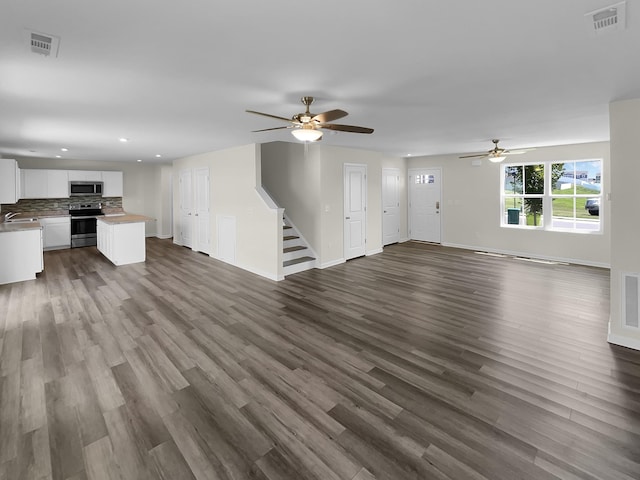 unfurnished living room with dark wood-type flooring, ceiling fan, and sink