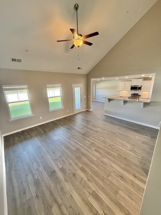 unfurnished living room featuring light hardwood / wood-style flooring, high vaulted ceiling, and ceiling fan