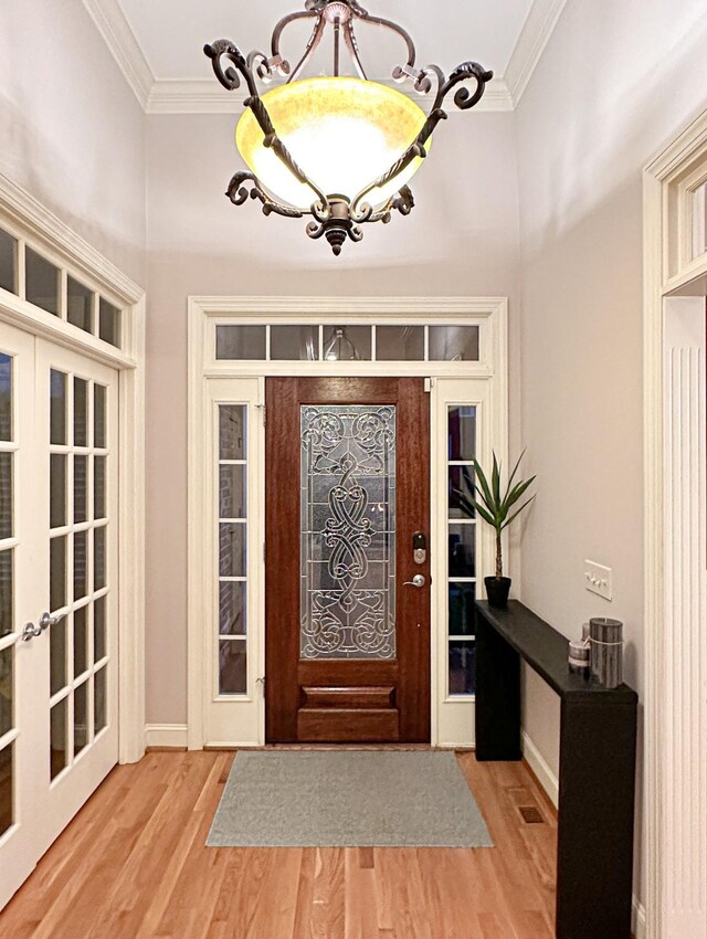 entrance foyer featuring light hardwood / wood-style flooring, french doors, and crown molding