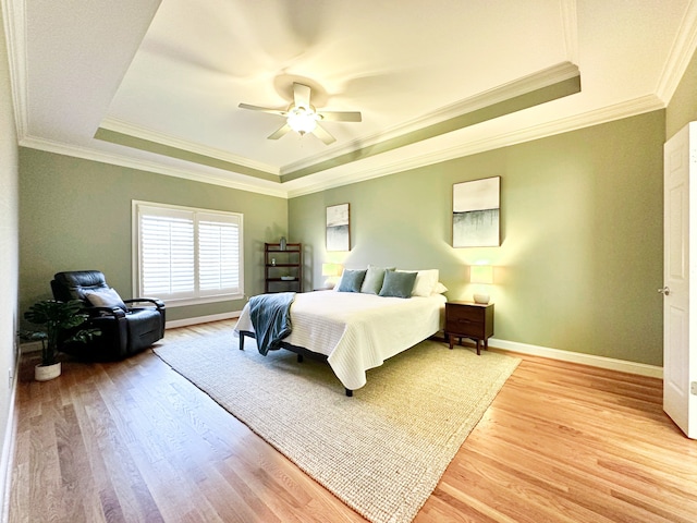 bedroom featuring light hardwood / wood-style flooring, a tray ceiling, and ornamental molding